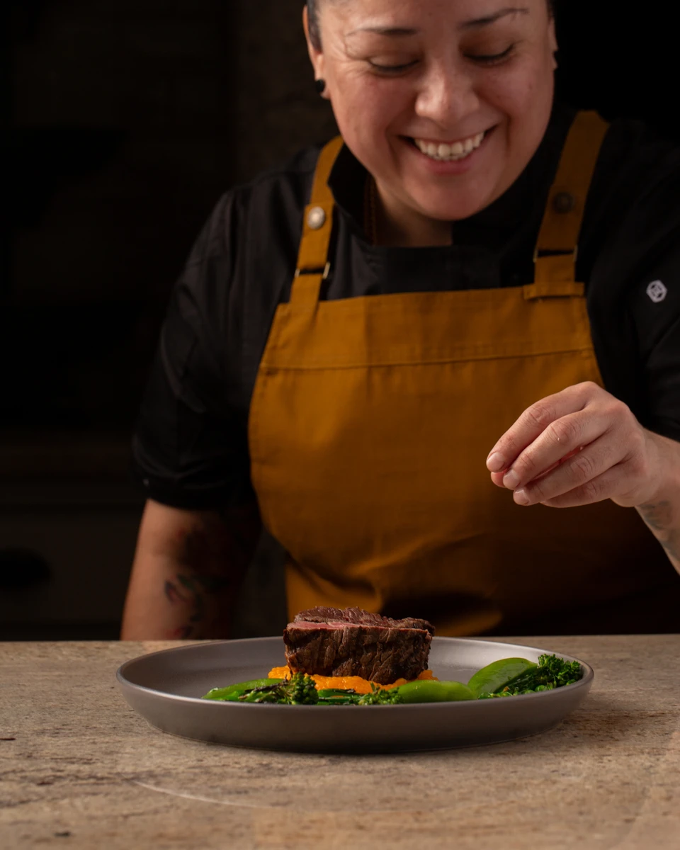 Chef Rosie Sanchez smiling while finishing a plate.