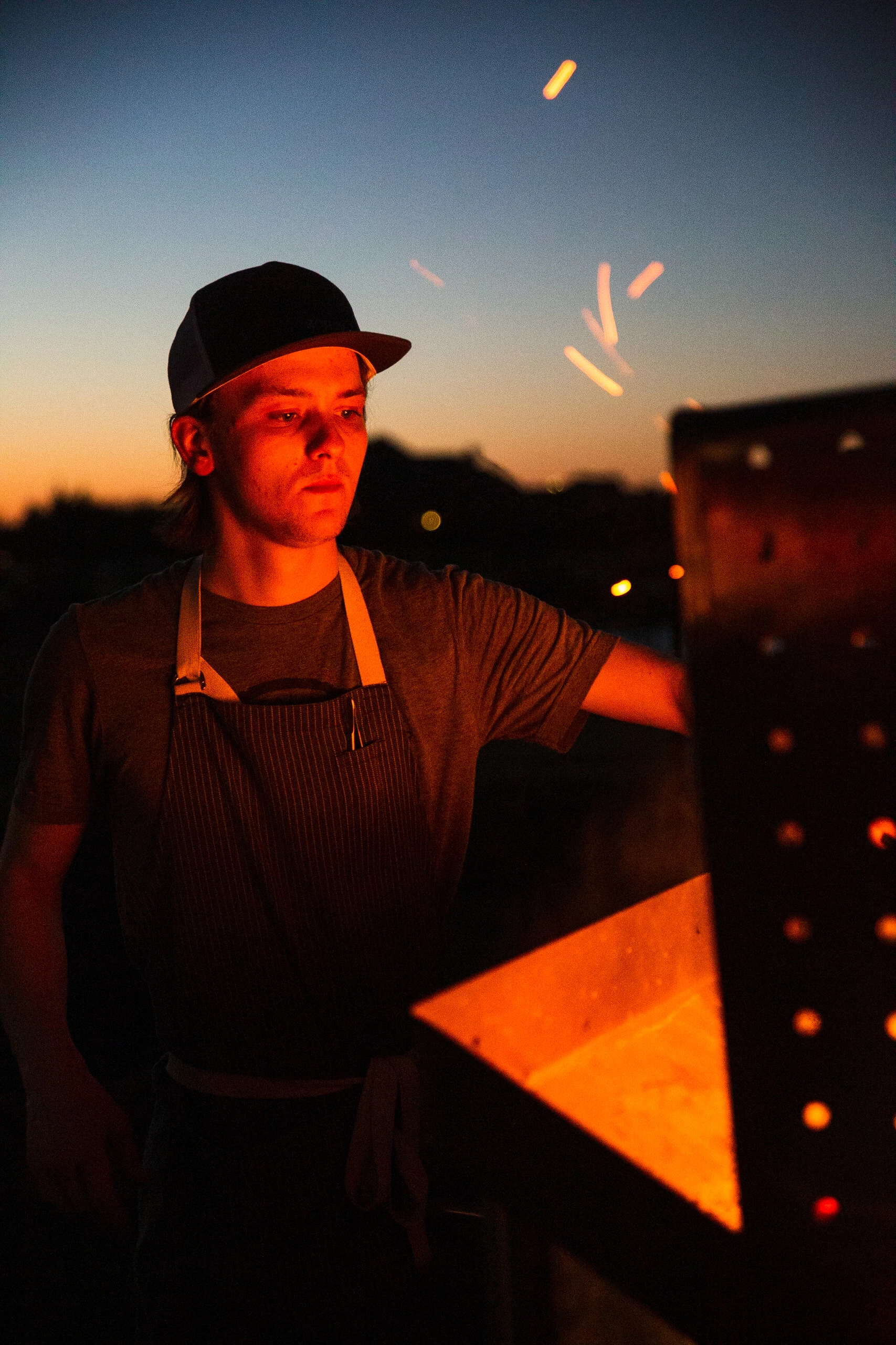 A cook lit by an outdoor fire at dusk.