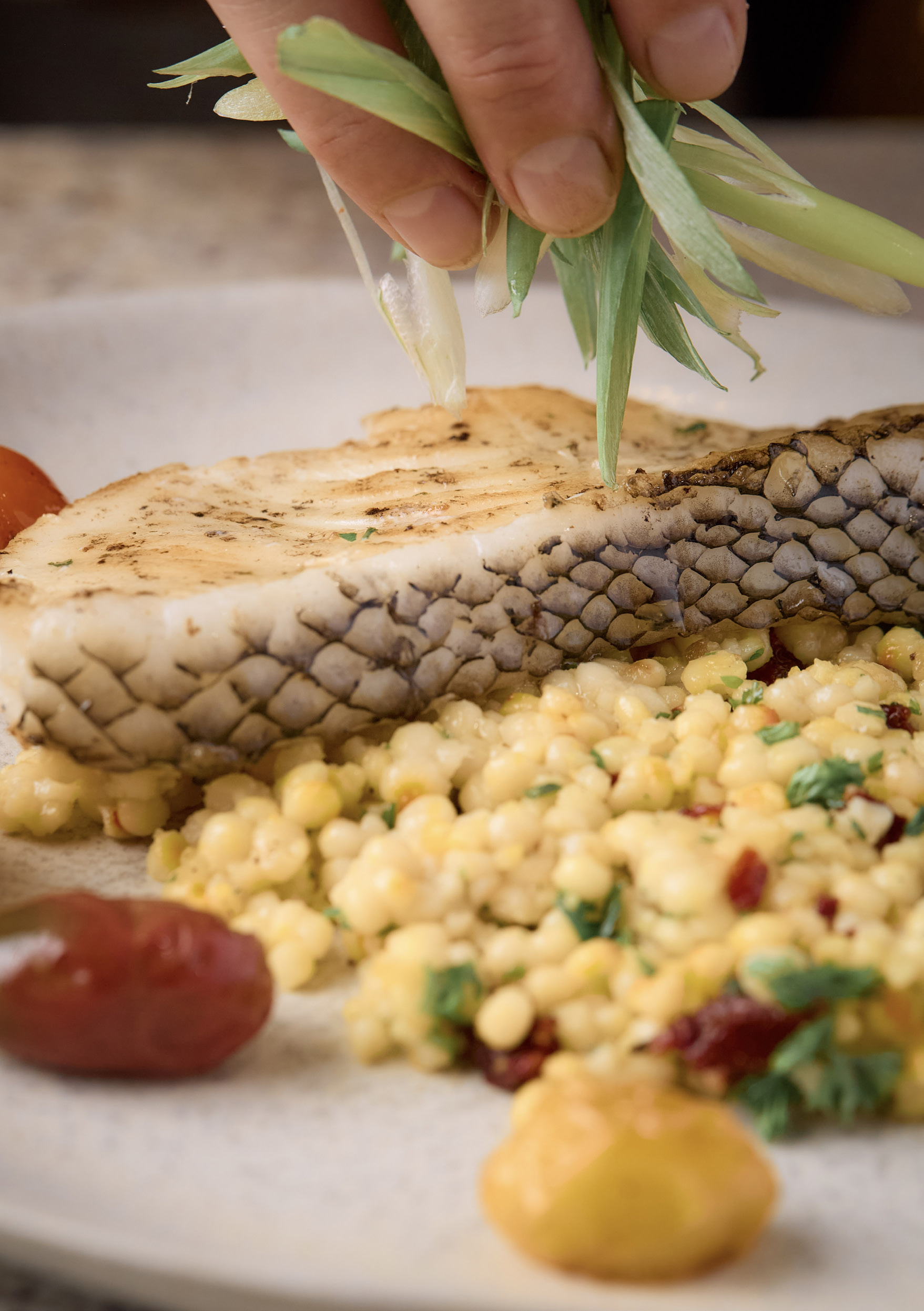 Rosie finishing a fish dish with fresh herbs.