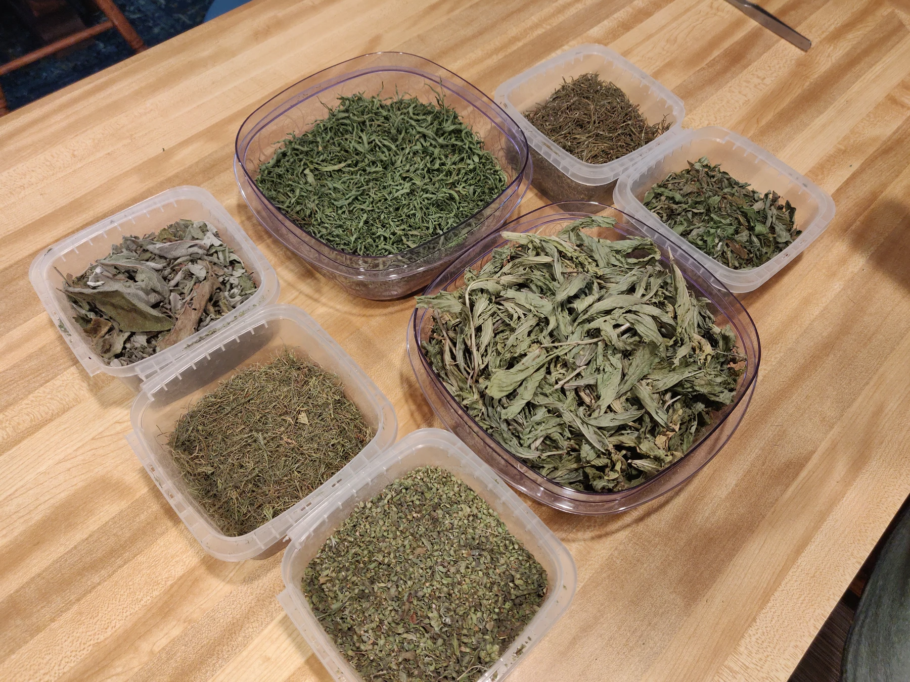 Sorted herbs and flowers in containers on the worktable.